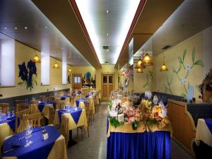 uma sala de jantar com mesas e cadeiras com toalha de mesa azul em Grand Hotel Rabbi em Bagni di Rabbi