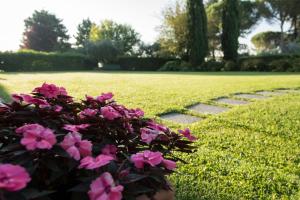 un arbusto con flores rosas junto a una pasarela en Borgo Villa Risi, en Siena