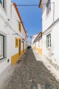 Une allée dans une ville avec des bâtiments blancs et jaunes dans l'établissement Casa Candeias, à Évora
