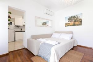 a white bedroom with a bed and a kitchen at Casa Candeias in Évora