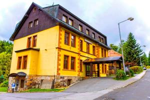 un bâtiment jaune avec un toit noir dans une rue dans l'établissement Penzion Adélka Janské Lázně, à Janské Lázně