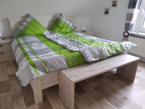 ein Bett mit grüner Bettwäsche und Kissen auf einer Holzbank in der Unterkunft Fehnhaus, Nordsee, Nähe Norddeich in Westermoordorf + 18 Fotos