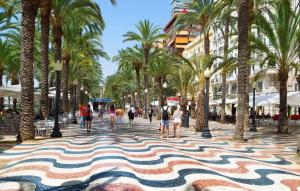 a street with palm trees and people walking down a sidewalk at Apartamento Vistahermosa in Alicante