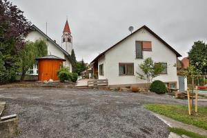 Biały dom z pomarańczowymi drzwiami i kościołem w obiekcie Zimmervermietung Familie Kolb w mieście Oberessendorf