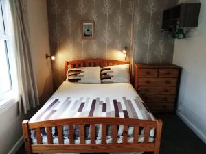 カイル・オブ・ロカルシュにあるCraig Cottageのベッドルーム(木製ベッド1台、ドレッサー付)