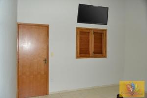 een kamer met een deur en een televisie aan een muur bij Recanto 4 Estações in Olímpia