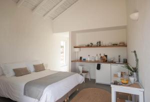 a white bedroom with a bed and a table at Alma Cheia Sunrise Studio Apartment in Odeceixe