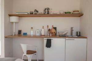 una cocina con un armario blanco con una mesa y una silla en Alma Cheia Sunrise Studio Apartment, en Odeceixe