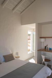 a white bedroom with a bed and a window at Alma Cheia Sunrise Studio Apartment in Odeceixe