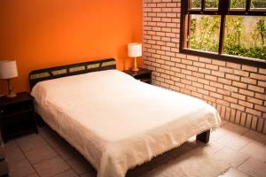 Pousada Mare Mansa في بومبينهاس: سرير في غرفة بها نافذتين