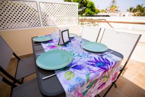 a table with blue plates on a colorful table cloth at Deluxe Apartment. 50 meters Beach in San Agustin