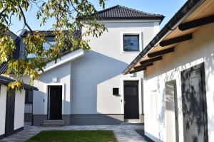 una casa blanca con puertas negras en Apartmany U Letiste, en Pardubice
