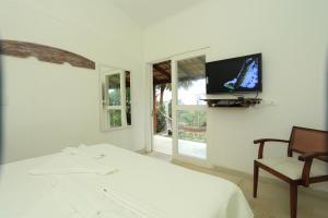 1 dormitorio con 1 cama, TV y silla en Chalés Mariolinha, en Ilhabela