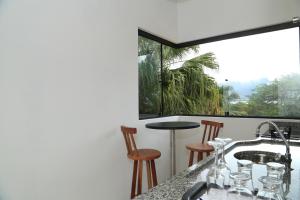 une cuisine avec une table et des chaises ainsi qu'une fenêtre dans l'établissement Chalés Mariolinha, à Ilhabela