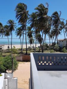 a view of a beach with palm trees and a building at Pousada Aconchego in Mundaú