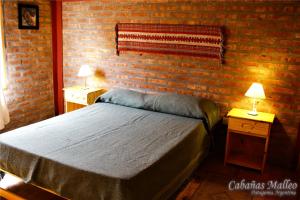 a bedroom with a bed and two tables with lamps at Cabañas Malleo in Junín de los Andes