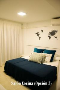 a bedroom with a bed with blue sheets and maps on the wall at Apartamento Botavara in Málaga