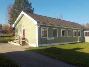 un pequeño edificio verde y blanco con porche en Hagfors Hostel en Råda