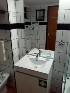 a white bathroom with a sink and a mirror at Casa do Espadarte in Sesimbra