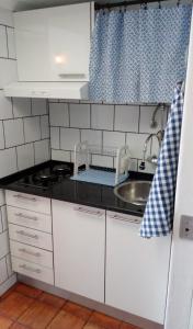 une petite cuisine avec des armoires blanches et un évier dans l'établissement Casa do Espadarte, à Sesimbra
