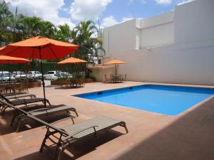 a pool with chairs and umbrellas next to a building at Hotel Marel in Poza Rica de Hidalgo