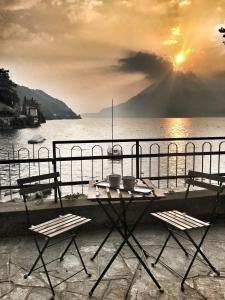 een tafel en stoelen op een balkon met uitzicht op het water bij gli oleandri in Bellano