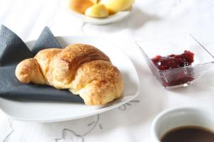 a plate with a croissant and a bowl of fruit at A Casa Romar in Turin