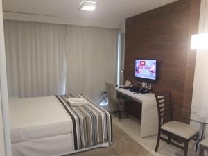 Dormitorio con cama, escritorio y TV en Fusion Executivo, en Brasilia