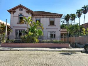 uma casa cor-de-rosa com uma vedação à frente. em Vila Santa Eulalia Hostel em Pelotas