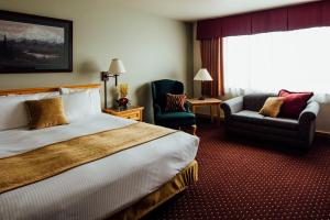 um quarto de hotel com uma cama e duas cadeiras e uma janela em Talkeetna Alaskan Lodge em Talkeetna