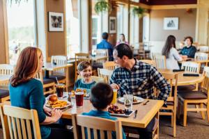 a family sitting at a table eating food in a restaurant at Talkeetna Alaskan Lodge in Talkeetna