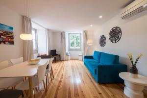 uma sala de estar com um sofá azul e uma mesa em Sunshine House - Exclusive Apartment - Home By The Castle em Lisboa