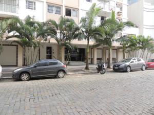three cars parked in front of a building with palm trees at Apartamento Confortavel em Balneário Camboriu in Balneário Camboriú