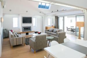 a living room with a couch and chairs and a tv at Luxurious Loft Apartments in the heart of Ahuriri in Napier