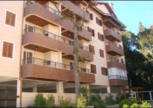 un edificio de apartamentos con un árbol delante de él en Flores da Montanha, en Gramado