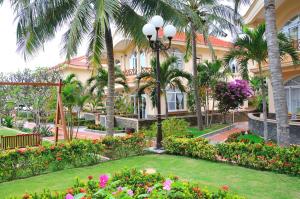 un edificio con palmeras y flores en un patio en Swiss Village Resort & Spa, en Mui Ne