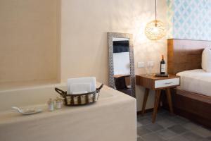 Quinta Margarita - Boho Chic Hotel في بلايا ديل كارمن: غرفة نوم مع سرير وطاولة مع زجاجة من النبيذ