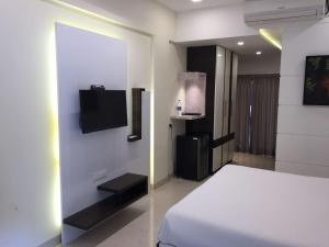 a bedroom with a bed and a tv on a wall at Hotel Rezo's in Baga