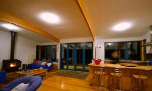 a living room with a kitchen and a stove at Mures Cloudy Bay Retreat in South Bruny