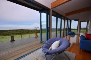 a living room with a blue chair on a deck at Mures Cloudy Bay Retreat in South Bruny