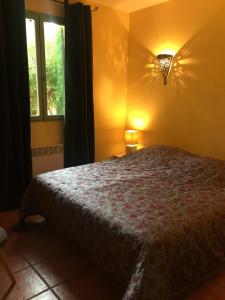 a bedroom with a bed and a light on the wall at Les Bastidons d'Angèle in Carpentras