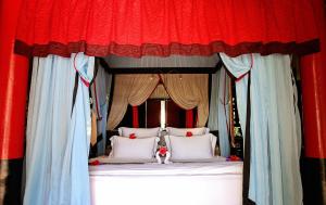 a bed with red and blue curtains and white pillows at Hotel Tugu Lombok - CHSE Certified in Tanjung