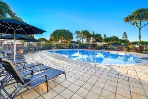 una piscina con tumbonas y sombrilla en Golden Riviera Absolute Beachfront Resort en Gold Coast
