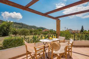 a patio with a table and chairs on a balcony at Villa Iliogenniti in Kalamaki
