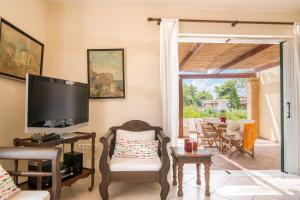 a living room with a television and a table with chairs at Villa Iliogenniti in Kalamaki