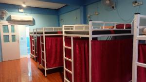 a room with four bunk beds with red curtains at Rehab Hostel in Phi Phi Don