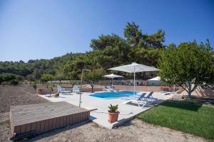 a swimming pool with chairs and an umbrella at The Olive Grove Villa Private Pool with star links WiFi in Theologos
