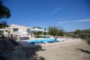 a house with a swimming pool with chairs and an umbrella at The Olive Grove Villa Private Pool with star links WiFi in Theologos