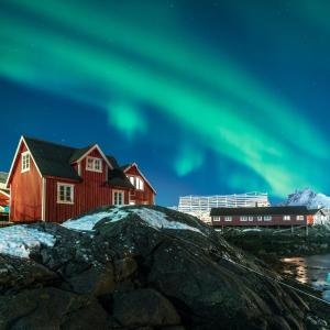 una imagen de la aurora boreal en el cielo sobre las casas en Svinøya Rorbuer, en Svolvær