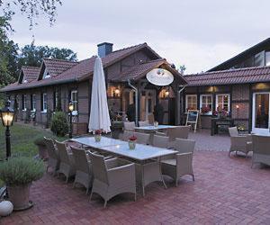 a patio with a table and chairs and an umbrella at Heidehotel Gut Landliebe in Hermannsburg +4 photos